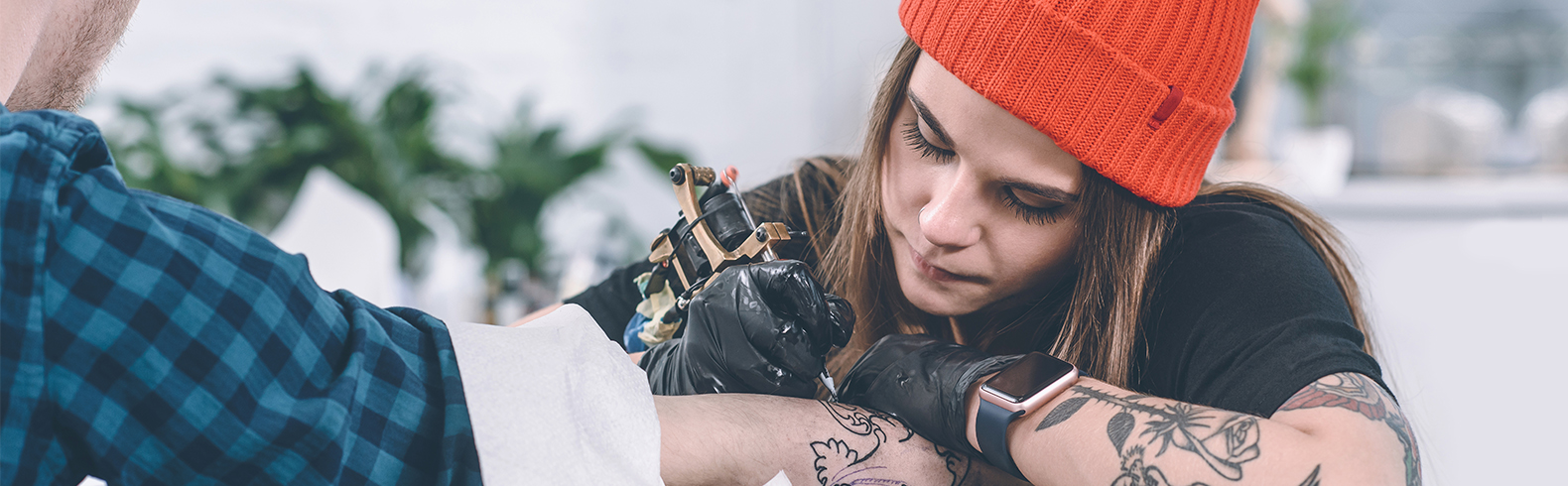 a woman is tattooing a man's arm