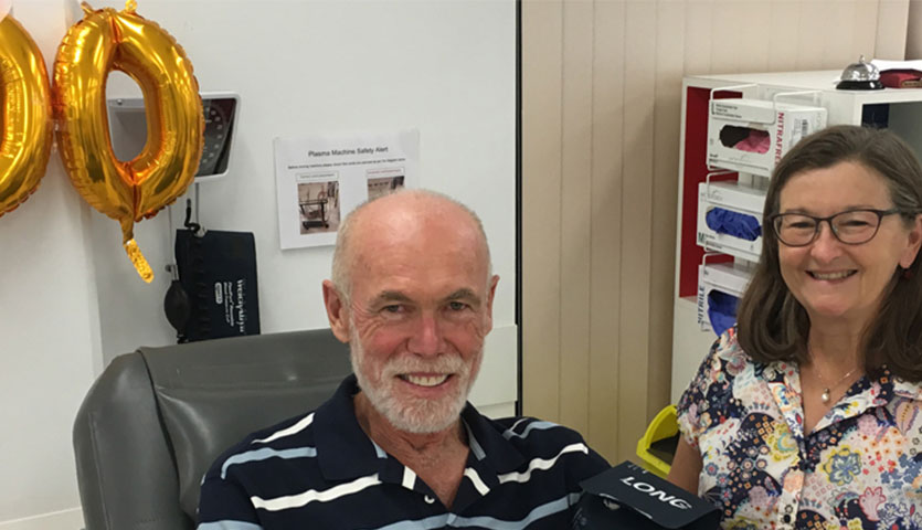 long term donor robert is seated in a donation chair with a nurse standing alongside him, both are smiling at the camera