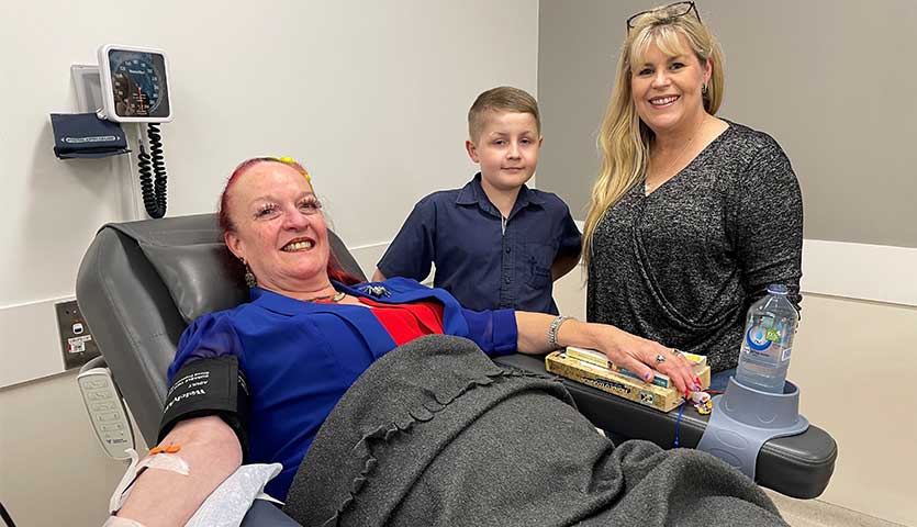 josh and kerryn miller are standing beside donor marieon schauer while she's donating