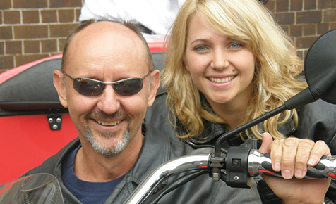 close up of recipient robert holloway and kelly seated on a motorbike, robert is wearing black sunglasses
