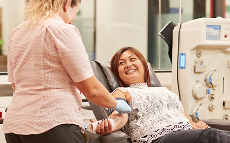 Woman giving blood smiling at nurse