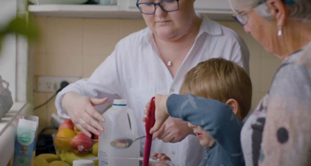 a family in a kitchen mixing food in a bowl
