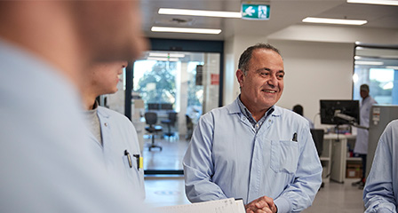 a group of scientists in a lab smiling and talking