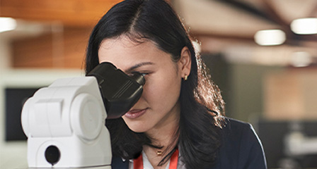 a woman looking into a microscope