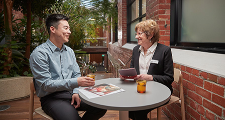 two staff members sitting at a lunch table talking and smiling