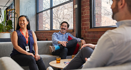 three staff members seated on couches in an office