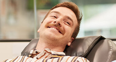 a male giving a donation in a chair smiling