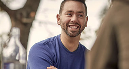 a man seated at a table at an outdoor cafe smiling