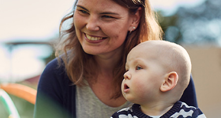 a mother sits with her child on her lap looking off camera and smiling