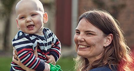 a mother and baby seated outside and smiling