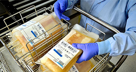 bags on plasma in a trolley with a lab worker picking one up