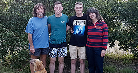 a family of four in a backyard with a dog beside them