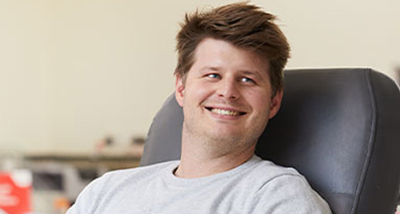 a male giving a donation in a chair smiling