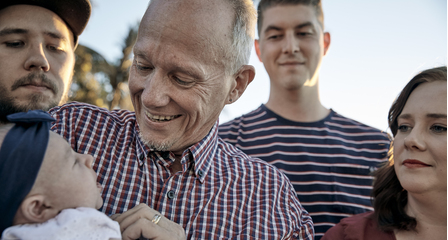 Blood donor Eric holding a child surrounded by smiling people