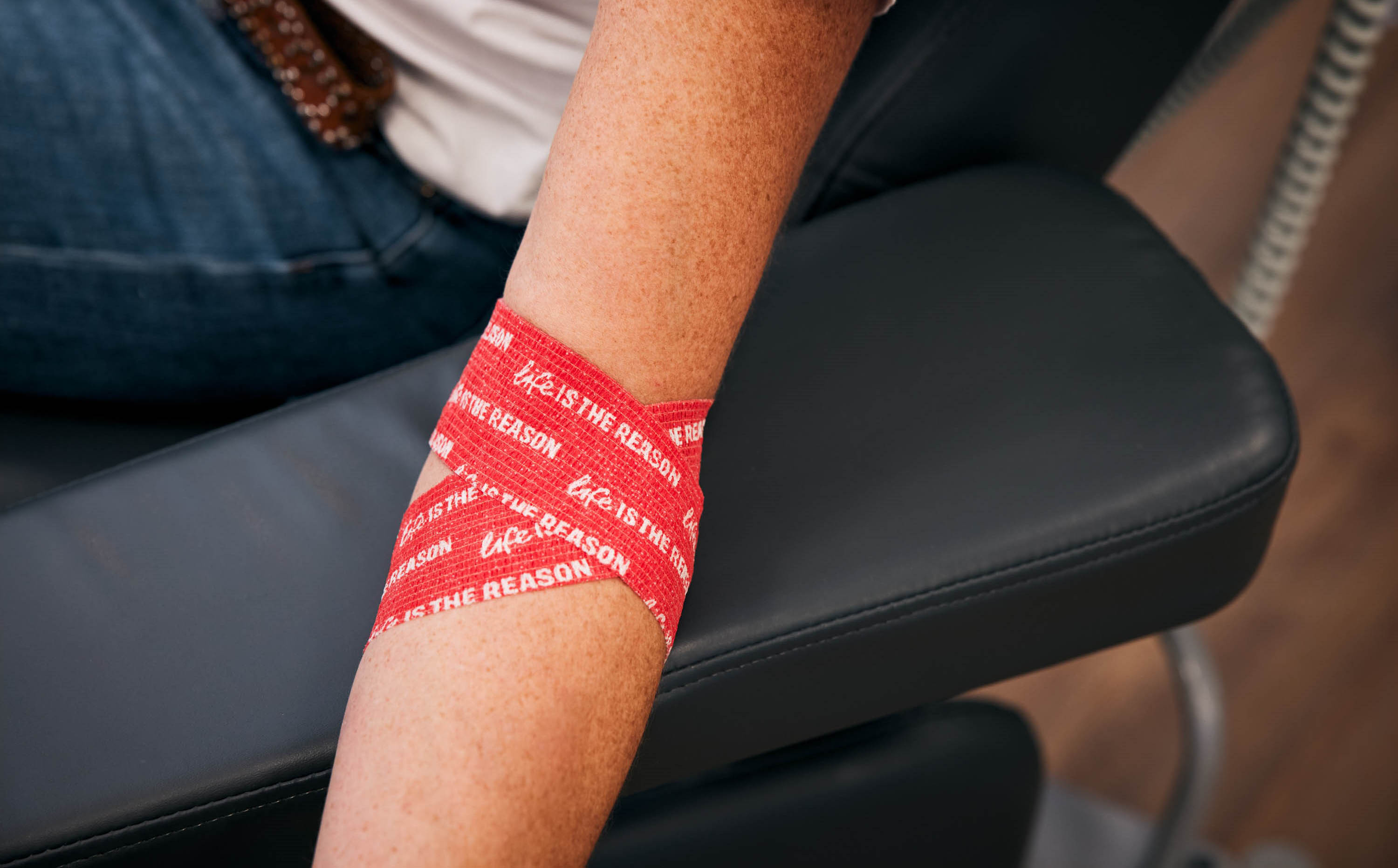 photograph of an arm wrapped in red life is the reason branded bandage