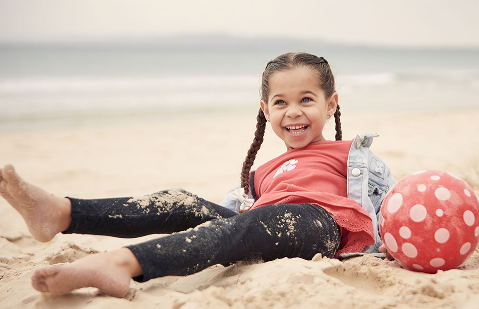 a child sitting on a beach and laughing