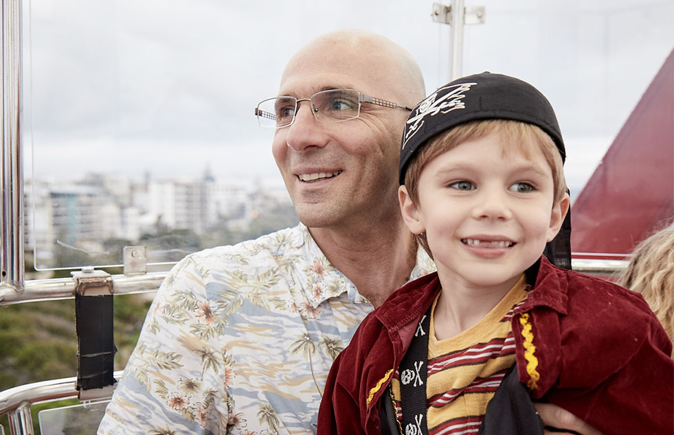 a father and son smiling with a cityscape in the background