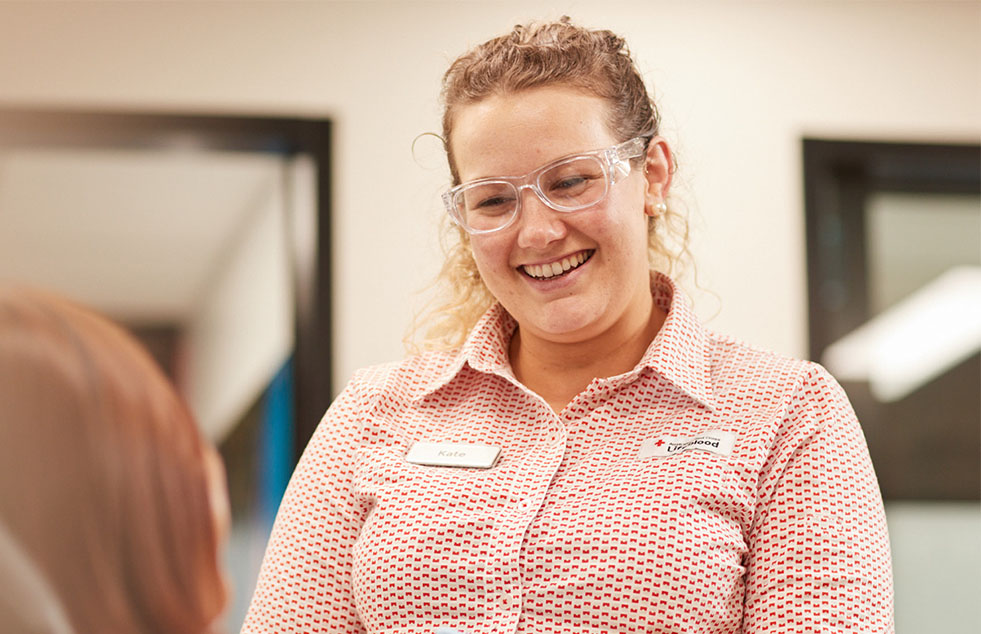 a nurse smilling at a person seated making a donation