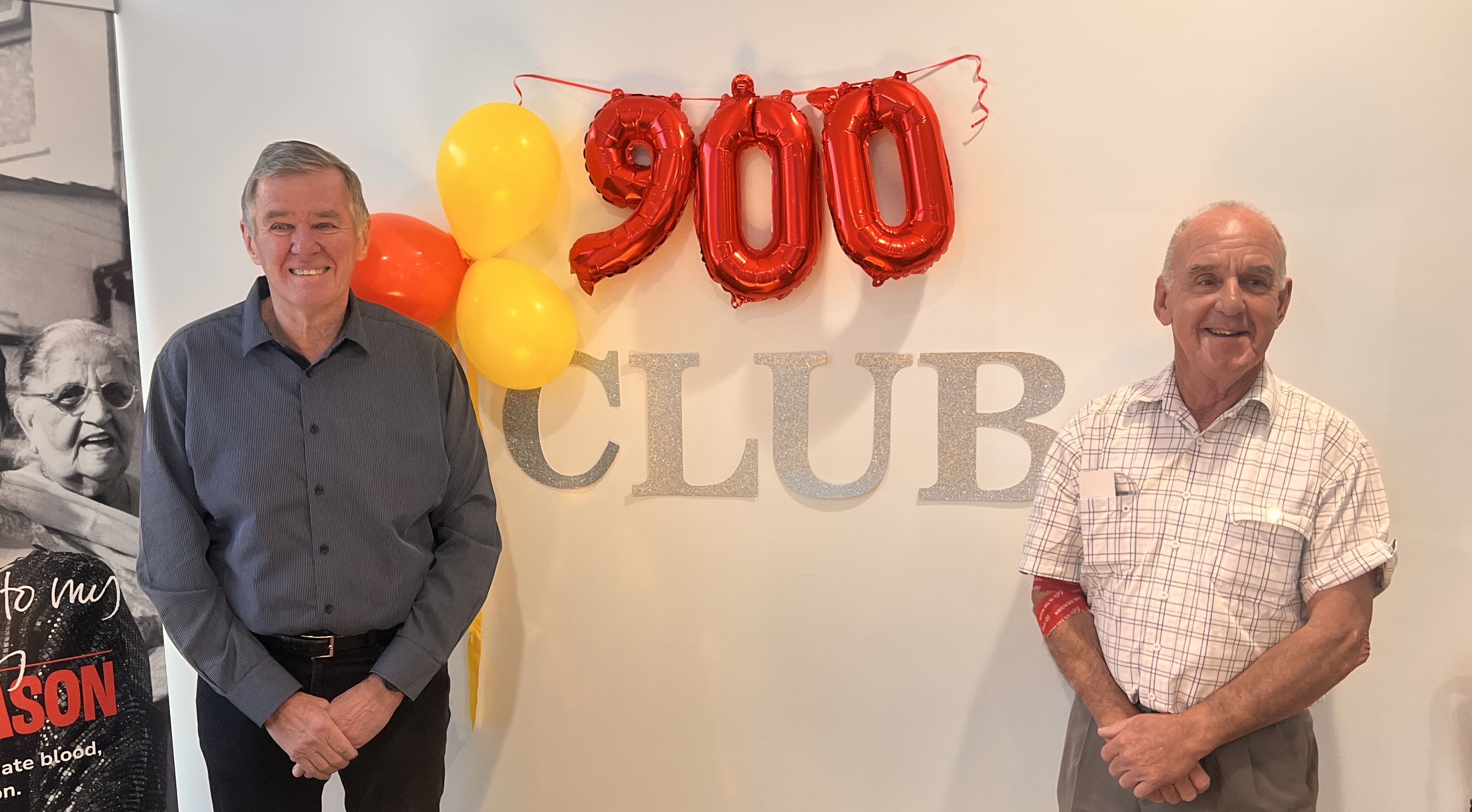 two men standing either side of a sign that reads 900 Club
