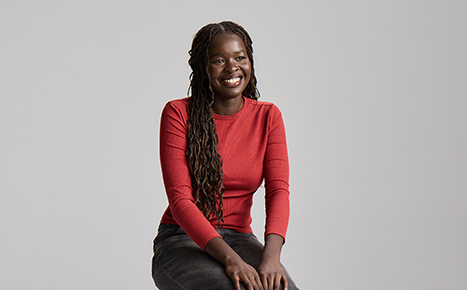 woman in red top sitting with hands on lap smiling
