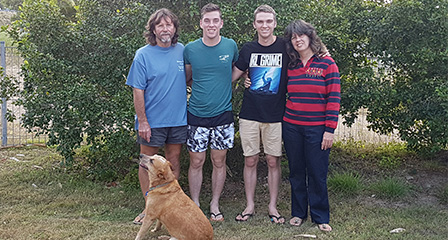 a family of four in a backyard with a dog beside them