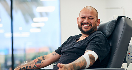 a male giving a donation in a chair smiling
