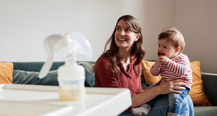 Mother holding small child with bottle of breast milk