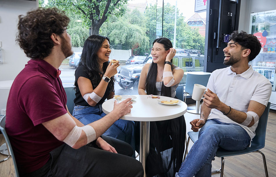 a group of people sitting around a table with snacks and drinks laughing and chatting