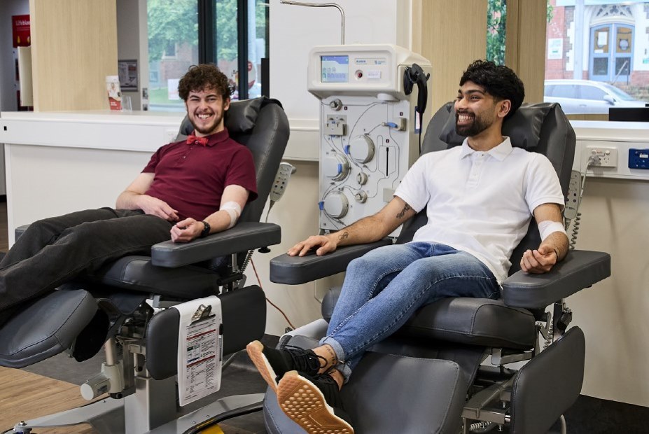 two people seated in donor chairs and smiling during a donation