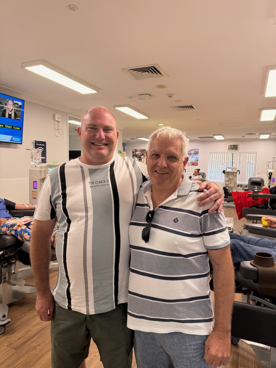 image of two males smiling at the camera in a donor centre