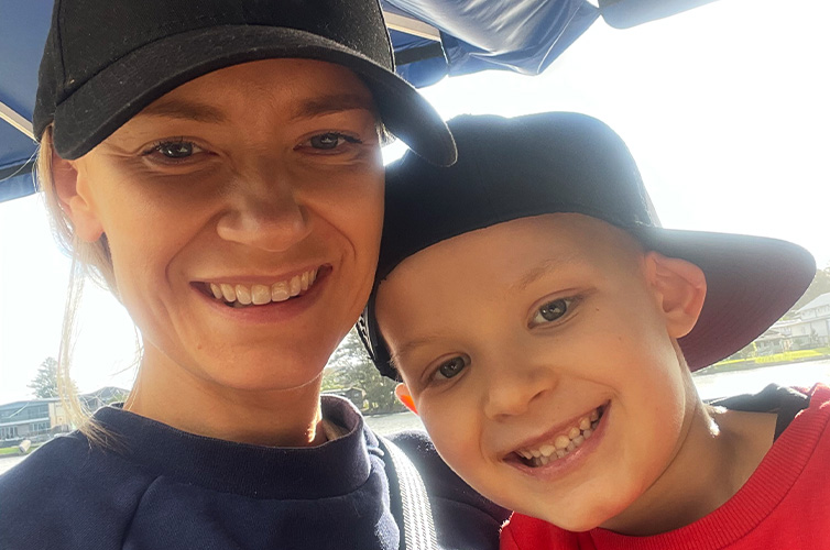young boy wearing a hat and his mother smiling at the camera