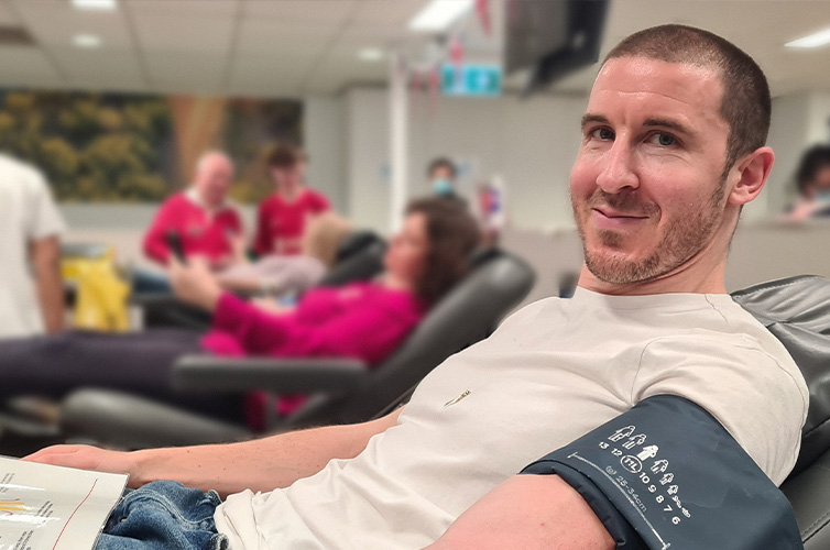 man smiling at camera while donating blood at a donor centre