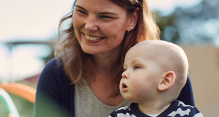 a mother sits with her child on her lap looking off camera and smiling