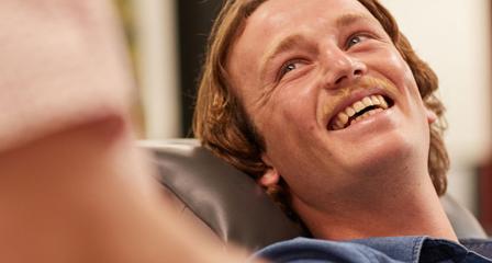 a donor is smiling sitting back in a seat looking up at a staff member