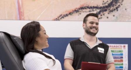 Donor Faye smiling in donor chair alongside Lifeblood staff Luke
