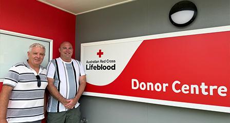 image of two middle-aged men in front of a Lifeblood donor centre sign