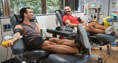 Image of two young male donors donating plasma next to each other