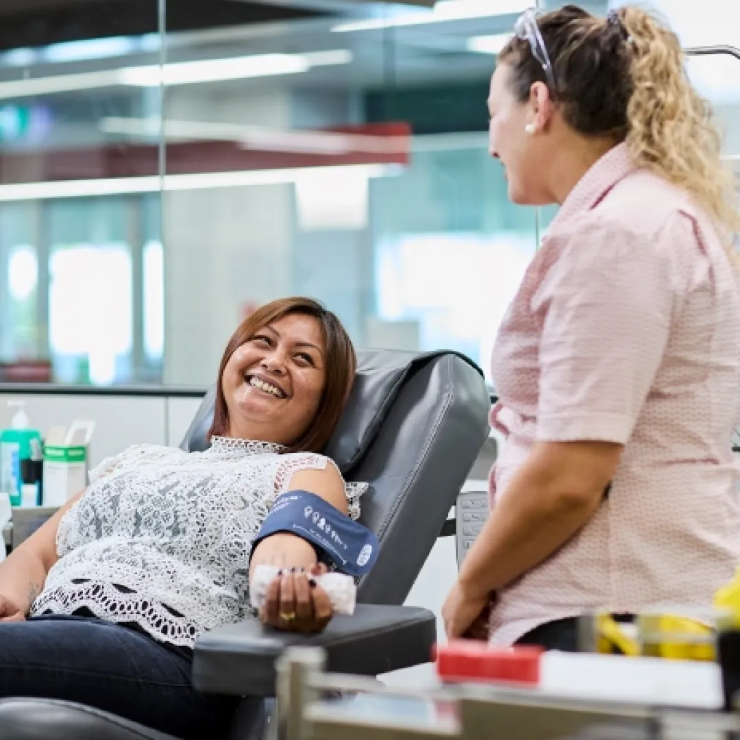 a person seated in a donor chair preparing for a donation with a staff member beside them