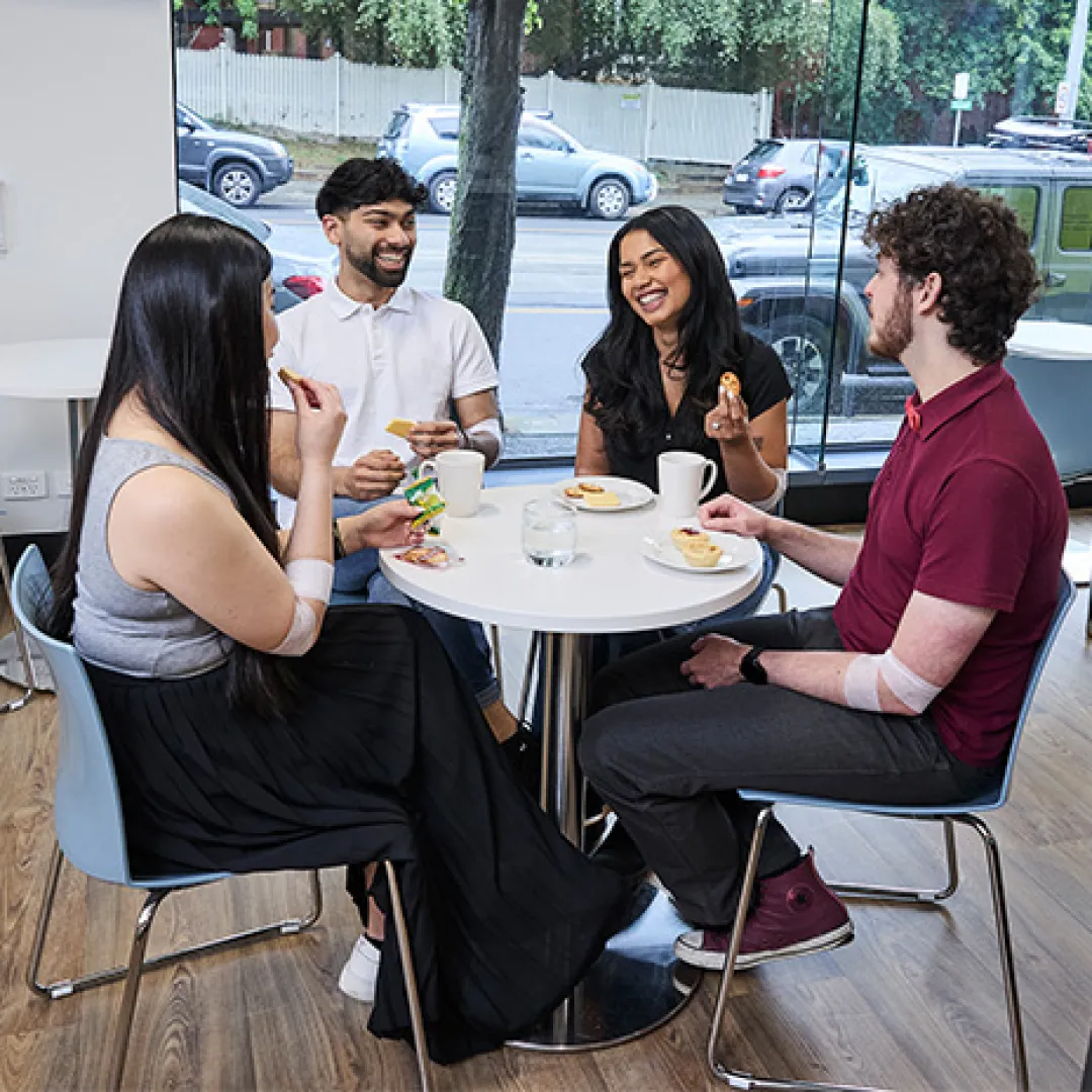 four people around a table chatting, eating snacks and drinking tea and water