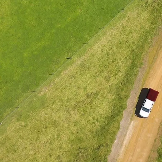aerial photo of a field with a car driving on a dirt road within it