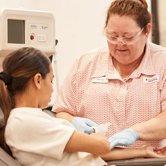 a donor is seated in a chair while a nurse prepares the donation