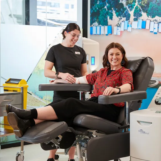 a donor is seated in a chair in a donor centre smiling