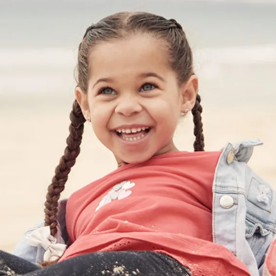 a child sitting on a beach and laughing