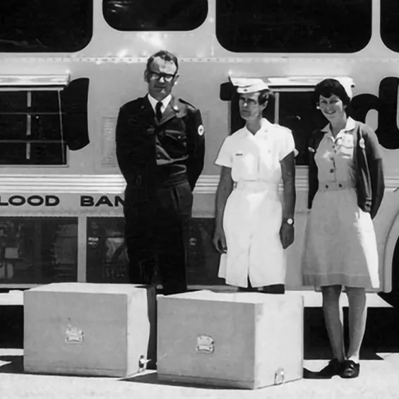 black and white photo of nurses and doctors standing in front of a red cross donation bus