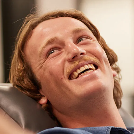 a male giving a donation in a chair smiling