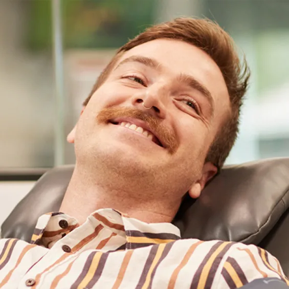 a male giving a donation in a chair smiling