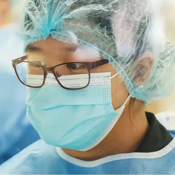 a lab technician wearing a blue gown and mask