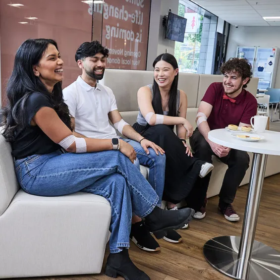 a group of people sitting around a table with snacks and water laughing and chatting