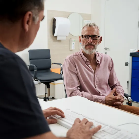 image of male doctor in front of keyboard talking to male patient