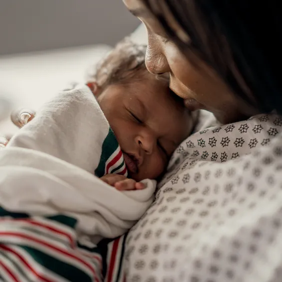 close up image of mother holding baby swaddled in blanket